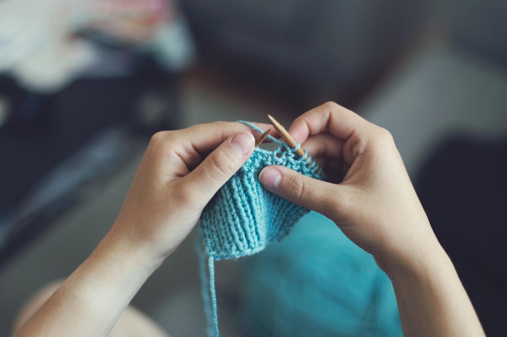 Hands knitting with blue yarn