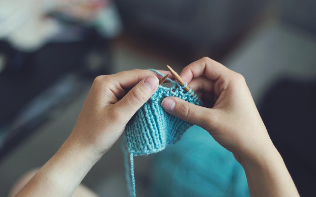 Hands knitting with blue yarn