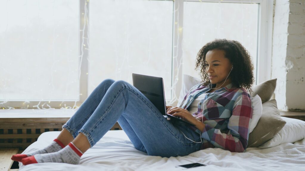 Woman looking at her laptop on her bed