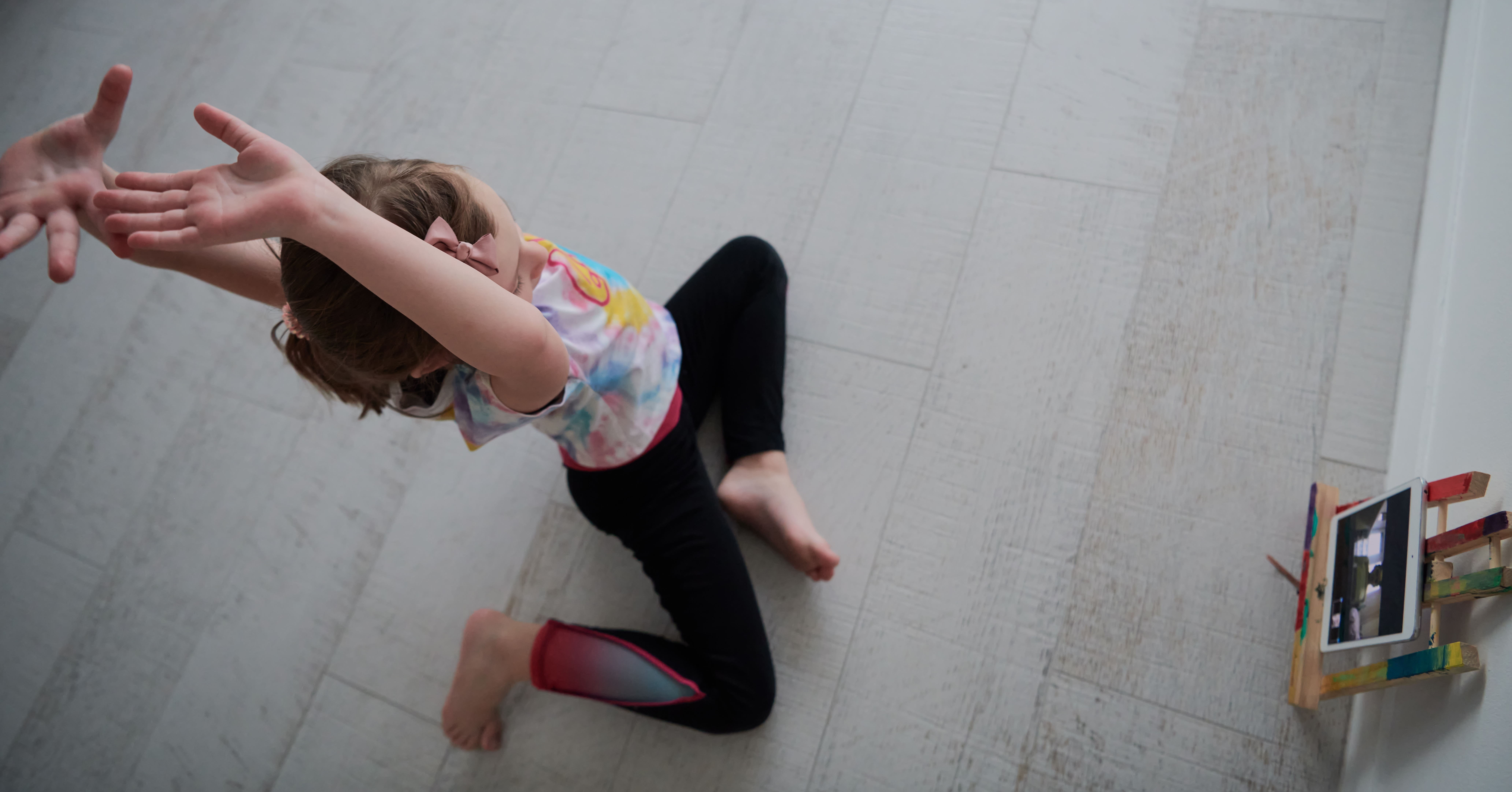 Little girl have online training over tablet and doing modern ballet dance exercise at home. Online education concept class in modern ballet school. Social distance during quarantine, isolation in coronavirus top view